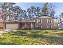 Charming brick home featuring a well-manicured lawn and covered porch at 4244 Newcomb Rd, Decatur, GA 30034