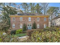 Traditional brick home featuring a symmetrical facade, lush landscaping, and a welcoming blue front door at 4146 Chadds Xing, Marietta, GA 30062