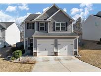 Charming two-story home featuring a two-car garage and gray siding at 7104 Skippingstone Way, Douglasville, GA 30134