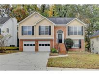 Two-story home boasts a two-car garage, brick accents, and manicured lawn, exuding curb appeal at 4224 Berkeley Mill Close, Duluth, GA 30096