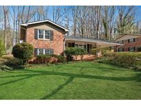 Charming brick home featuring a lush green lawn and a covered front porch, nestled among mature trees at 731 Fern Se St, Marietta, GA 30067
