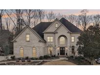 Stately brick home featuring a well-manicured lawn and charming front porch seating area at 10235 Worthington Mnr, Suwanee, GA 30024