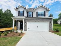Two-story home featuring a brick and vinyl facade, a two-car garage, and a well-manicured front lawn at 145 Scarlett Place Dr, Bowdon, GA 30108