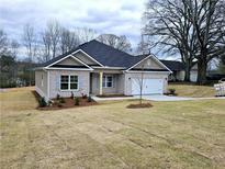 Charming one-story brick home featuring a manicured front lawn, attached garage, and neutral colored trim and shutters at 116 Scarlett Place Dr, Bowdon, GA 30108