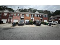 Townhouse exteriors featuring brick facades, attached garages, and neat landscaping under a cloudy sky at 1552 Viero Dr, Lawrenceville, GA 30044