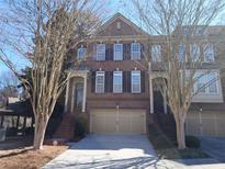 Charming brick townhouse with a two-car garage, inviting entrance, and manicured landscaping at 2855 Overlook Trace, Atlanta, GA 30324