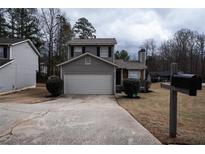 Two-story home featuring gray siding, a two-car garage, and well-maintained landscaping at 3934 Conley Downs Ln, Decatur, GA 30034