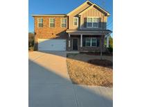Two-story home featuring a brick facade, neutral siding, attached two-car garage and covered front porch at 3923 Rustic Barn Way, Loganville, GA 30052