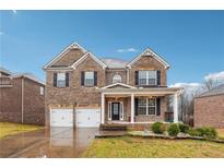 Charming two-story brick home featuring a two-car garage, covered porch, and manicured front lawn on a sunny day at 657 Vendella Cir, Mcdonough, GA 30005
