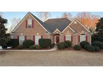 Charming brick home features a well-manicured lawn, colorful shutters, and beautiful landscaping at 8008 Revere Dr, Mcdonough, GA 30252