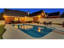 Stunning backyard pool with outdoor dining and deck seating at dusk for relaxation and entertainment at 1408 Aramore Dr, Conyers, GA 30013