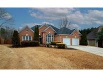 Charming brick home featuring a manicured lawn, trimmed hedges, and a two-car garage at 165 Arbor Creek Way, Roswell, GA 30076