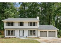 Charming two-story home boasts a manicured lawn, neutral siding, and a two-car garage, nestled among mature trees at 3228 Huntwood Dr, Decatur, GA 30034