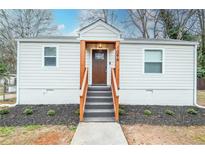 Charming bungalow with wooden door and stairs, landscaped front yard, and ample natural light at 1096 Ferndale St, Stone Mountain, GA 30083