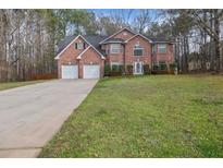 Traditional brick home with a well-manicured front lawn and an extended driveway at 504 Trotters Ln, Mcdonough, GA 30252