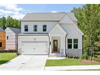 Charming two-story home boasts a welcoming front porch and attached two-car garage at 104 Cedar Brook Dr, Holly Springs, GA 30115