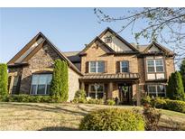 Handsome two-story brick home with stone accents, manicured lawn, and inviting covered front porch at 4025 Toulon Ln, Cumming, GA 30040