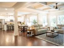 Spacious living room featuring hardwood floors, coffered ceilings, and open-concept design into kitchen at 4025 Toulon Ln, Cumming, GA 30040