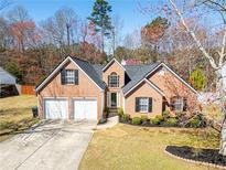 Charming brick home features a two-car garage, well-manicured lawn, and mature landscaping at 3412 Hard Creek Ln, Buford, GA 30519