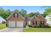 Charming brick home with a well-manicured lawn and a two-car garage provides appealing curb appeal at 3412 Hard Creek Ln, Buford, GA 30519