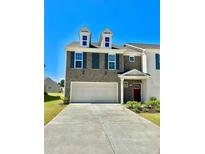 Beautiful two-story townhome with a three car garage, landscaped yard, and neutral brick facade at 2560 Quarterdeck Dr, Cumming, GA 30041