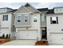 Charming townhome showcasing a white brick facade, carriage style garage door, and a neatly landscaped front yard at 1307 Fern Ridge Ct # 25, Norcross, GA 30093
