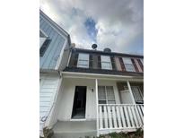 Two-story townhome with neutral colors, well-kept facade and open front porch at 498 Prince Of Wales, Stone Mountain, GA 30083