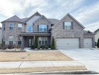 Stately gray brick home with manicured landscaping, three car garage and inviting curb appeal at 3988 Two Bridge Drive, Buford, GA 30519