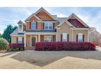 Charming two-story home featuring a manicured lawn, brick accents, and a welcoming front porch at 1053 Island View Ct, Buford, GA 30518