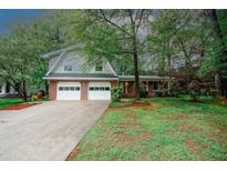 Charming two-story home features a brick facade, attached two-car garage and a well-manicured front lawn with mature trees at 4144 Hideaway Dr, Tucker, GA 30084