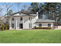 Stately two-story home with a manicured lawn, white painted brick, black trim and classic architectural details at 2283 Stratmor Dr, Tucker, GA 30087