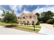 Charming two-story brick home featuring a manicured lawn and a long driveway at 1236 Saxony Se Dr, Conyers, GA 30013