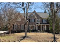 Charming two-story brick home with a manicured lawn, dark shutters, and a welcoming front porch at 1615 Chattahoochee Run Dr, Suwanee, GA 30024