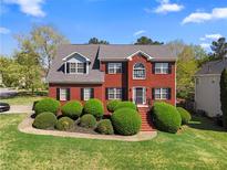 Charming two-story brick home with lush landscaping and a well-manicured front lawn on a sunny day at 1710 Brandon Lee Sw Way, Marietta, GA 30008