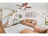 Inviting living room featuring a comfortable leather sofa, stylish decor, and a ceiling fan for added comfort at 44 Hall Mnr, Alpharetta, GA 30022