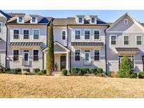 Charming three-story townhome with a manicured front yard and classic architectural details at 10035 River Rock Dr, Roswell, GA 30076
