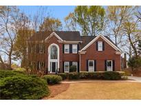 Beautiful two-story brick home with mature landscaping and a manicured lawn at 755 Creek Wind Ct, Johns Creek, GA 30097
