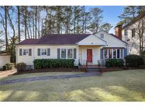 Charming home with a red front door, complemented by lush landscaping and a well-manicured lawn at 1258 Merry Ne Ln, Atlanta, GA 30329