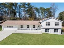 Inviting split-level home featuring a manicured lawn, white painted brick, and charming front porch at 4554 Mountain Creek Ne Dr, Roswell, GA 30075