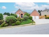Charming red brick home with a manicured front yard and a two-car garage on a picturesque street at 11385 Donnington Dr, Duluth, GA 30097