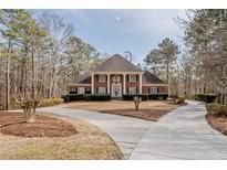 Stately brick home with a circular driveway and mature trees on a large lot at 3968 Belle Glade Ct, Snellville, GA 30039