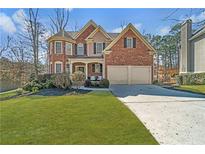 Charming two-story red brick home featuring a well-manicured lawn and an attached two-car garage at 1654 Summersweet Ln, Dacula, GA 30019