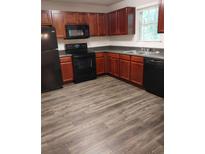 Traditional kitchen featuring wood cabinets, black appliances, and laminate floors at 5175 Hanover St, Atlanta, GA 30349
