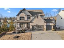 Charming two-story brick home with a covered porch and a three-car garage on a well-maintained lawn at 7630 Rambling Vale, Cumming, GA 30028