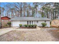 Charming, light gray brick ranch-style home with attached garage and mature trees in a serene setting at 6510 Connell Rd, Atlanta, GA 30349