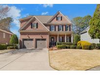 Charming two-story red brick home featuring a manicured lawn, symmetrical windows, and a two-car garage at 1835 Leighton Ne Ln, Marietta, GA 30062