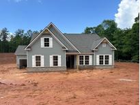 Charming single-Gathering home featuring light gray siding, a gray roof, white trim, and a brick foundation at 1239 Pj East Rd, Covington, GA 30014