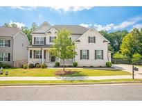Charming two-story home with white brick, black shutters, green lawn, and a neatly paved driveway at 384 Carmichael Cir, Canton, GA 30115