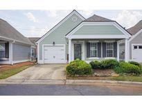 Charming, light-green, single-story home featuring a well-manicured yard and attached one-car garage at 134 Rose Cottage Ln, Woodstock, GA 30189