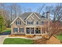 Charming two-story home with a well-manicured lawn, covered porch, and blue shutters at 7270 Sheffield Pl, Cumming, GA 30040